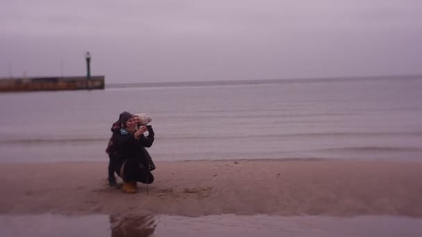 Mamá y su hija toman una foto en el fondo del muelle del mar y el mar de invierno.familia Selfi — Vídeos de Stock