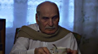 Beyaz adam evde çay içiyor.