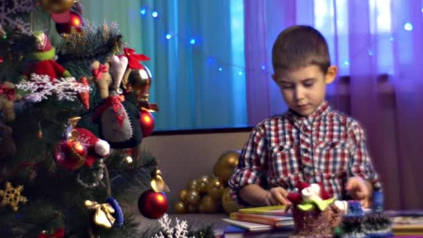 Menino Assistindo Livro Perto Árvore Natal Casa — Vídeo de Stock
