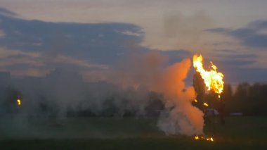 Ateş yakan adamlar, alacakaranlıkta siluetler. Erkekler koşuyor, Ateşin etrafında yürüyor, Duman yükseliyor. Ağır çekim. Büyük Yanan Meşaleler. Ulusal Tatil, Şehrin Sınırında Gösteriler