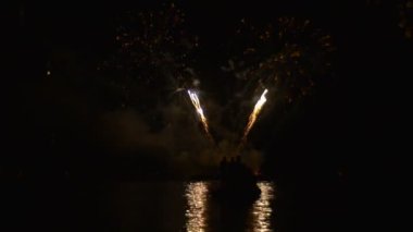 Göldeki Güzel Havai Fişek Gösterisi Geceleyin w harfi, V kompozisyonu, parlak renkli kıvılcımlar suya düşer. Havai fişek gösterisi, yüksek sesli silah sesleri.