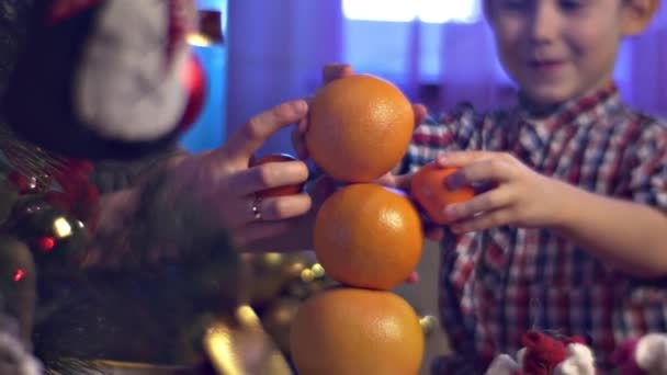 Matka Syn Bawią Się Pomarańczami Mandarynkami Pobliżu Choinki Domu — Wideo stockowe