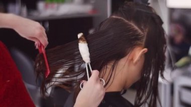 Spa salonunda kadın müşterinin saçını tarayan kuaför.