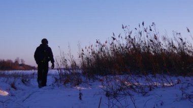 Kış sabahının erken saatlerinde donmuş gölde zaman geçiren bir adamın silueti.