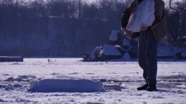 İnsan kışın donmuş gölde büyük bir buz parçası alıp taşır.