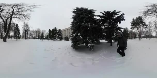 360Vr Video L'uomo cammina sulla neve nel parco intorno a Firs Fare passi e riprese intorno agli alberi Natura dell'Ucraina Konotop in vacanze invernali all'aperto Silhouette — Video Stock