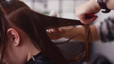 Spa salonunda kadın müşterinin saçını tarayan kuaför.