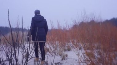 Soğuk bir sonbahar ya da kış gününde dışarıda yürüyen bir kadın.