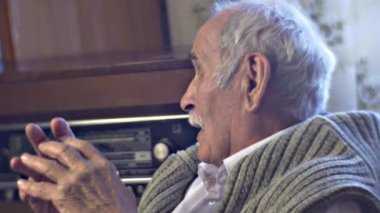 Kafkasyalı kıdemli adam evde retro radyo dinliyor.