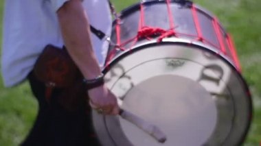 Gri sakallı davulcu bir sahada yürüyor