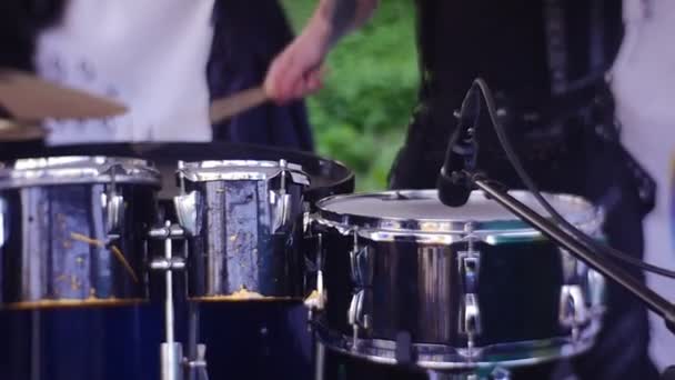 Concerto musical de verão ao ar livre, um baterista em roupas de concerto preto toca um conjunto de tambores com música rítmica com pauzinhos — Vídeo de Stock