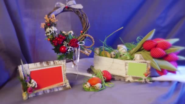 Mesa con un tradicional anillo marrón católico cristiano de Pascua con flores de campo, tulipanes rosados, huevos de gallina y codorniz, tarjetas de diapositivas, un marco fotográfico, en él — Vídeo de stock