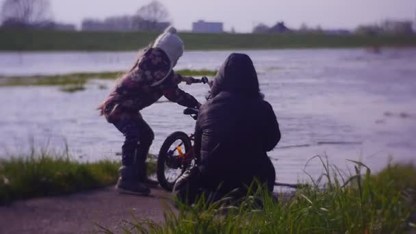 Liten flicka som försöker dränka hennes cykel i floden — Stockvideo