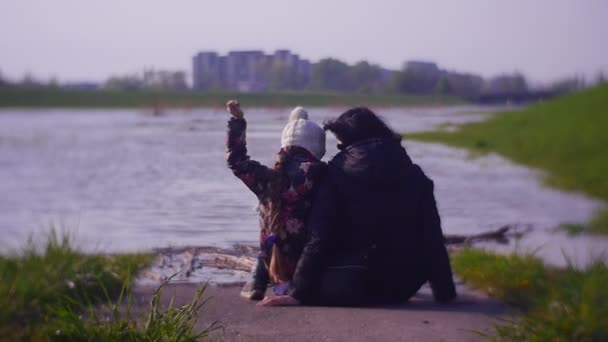 Ung mor med barn vilar på flodstranden — Stockvideo
