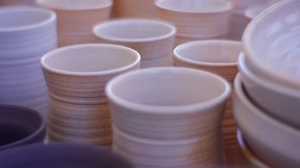 Um monte de pequenas placas de barro Canecas e jarros Panorama dos objetos Vasos de exposição são cobertos com esmalte Arte dos tempos antigos Oficina de cerâmica ao ar livre — Vídeo de Stock