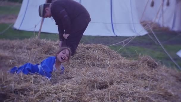 Lovagi játékok Opole középkori ruházati fiú és lány boldog gyerekek játszanak rakás szalma történelmi Reenactment egy tábor középkori harcosok — Stock videók
