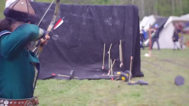 Uzun saçlı Archer hareketli hedefleri Ortaçağ Festivali okçuluk antik okçuluk aksesuarları ortaçağ kostümleri için elbise giyim çadırlar arasında orman vuruyor. — Stok video