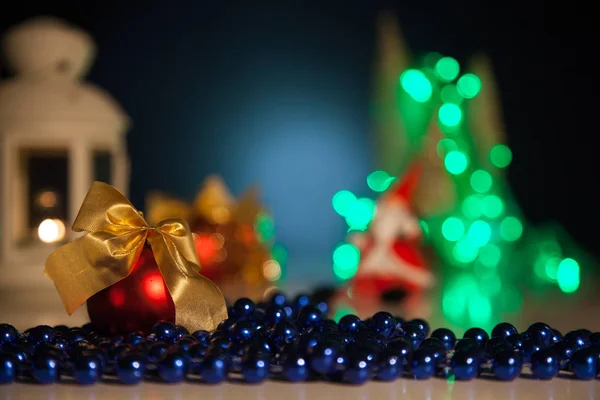 Palla di Natale rossa con perline su uno sfondo di luci — Foto Stock
