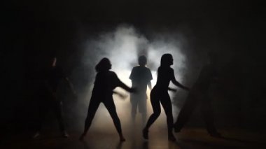 Beş dansçı duman karanlıkta dans ediyor.