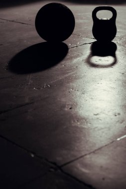 Kettlebell ve topu arka ışık ve gölge içinde jimnastik salonu