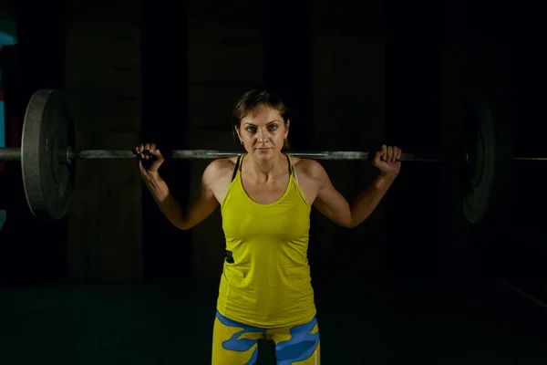 Chica joven haciendo sentadilla de servicio pesado en el gimnasio con barra . — Foto de Stock