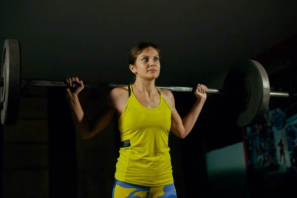 Mujer joven levantando una barra en el gimnasio — Foto de Stock