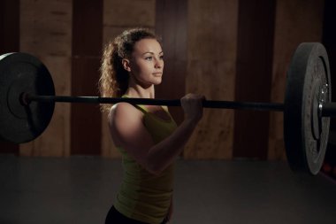 Tek omuzlu bir halter tutan genç kadın.