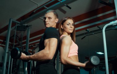 Erkek ve kadın spor salonunda dumbbells ile.