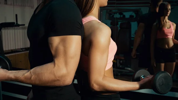 Mann und Frau mit Kurzhanteln im Fitnessstudio. — Stockfoto