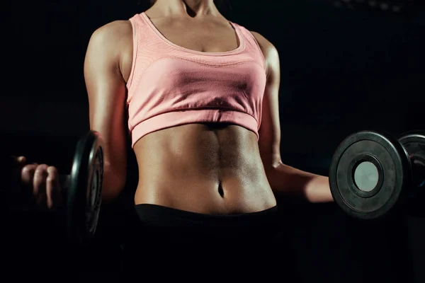 Beautiful body of a young woman with dumbbells in his hands. — Stock Photo, Image