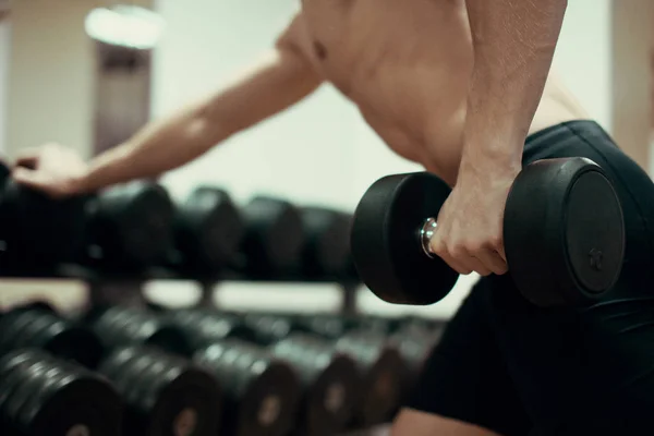 Крупный план мускулистого молодого человека, поднимающего тяжести в спортзале . — стоковое фото