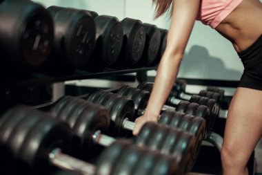 Genç kız bir dumbbell alır.