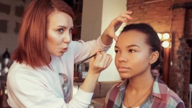 Makyöz makyaj yapıyor güzel Afrikalı model.