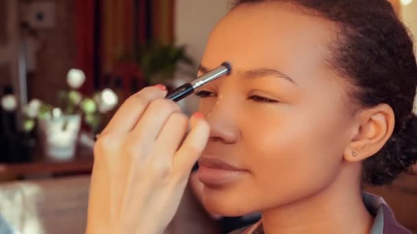 Maquillaje artista haciendo maquillaje para joven hermosa mulata . — Vídeo de stock