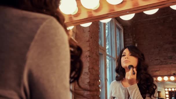 Mooi meisje maakt een make-up voordat een spiegel — Stockvideo