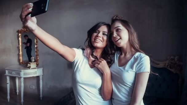 Hermosas chicas sonrientes en camiseta blanca mueca y hacer selfie con el teléfono inteligente . — Vídeos de Stock