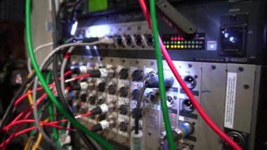 Dengeleyiciyi, yükselticiyi, hoparlörleri ve diğer müzik aletlerini bağlamak için bağlantı kablolarına sahip konser ekipmanları