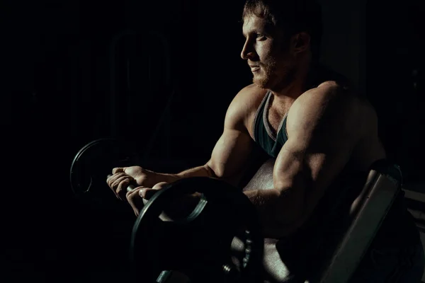 Um atleta atleta bonito jovem close-up que está fazendo um exercício com um sino. ginásio. bíceps. Fisiculturista — Fotografia de Stock