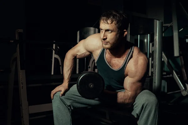 Jeune athlète sautant, posant avec des haltères dans la salle de gym montrant un biceps pompé. Bodybuilder — Photo