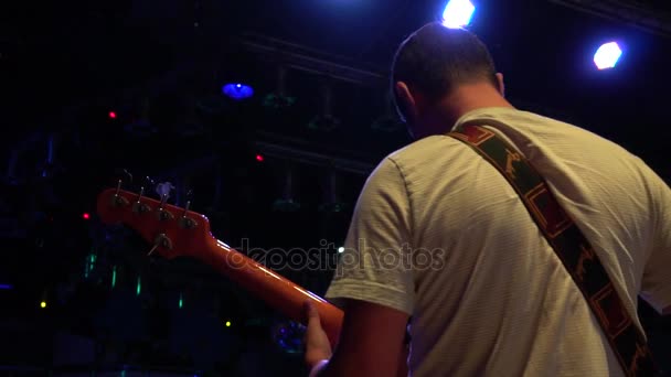 De muzikant speelt een akoestische gitaar bij een rockconcert onder de flikkerende lichten — Stockvideo