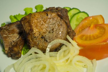 Soğan, salatalık ve domates ve bir salata ile beyaz bir plaka üzerinde sulu ızgara et. yakın çekim.