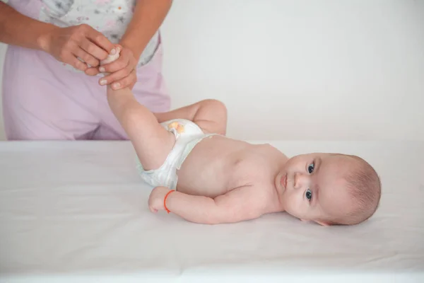 El médico masajea la pierna de un niño sobre un fondo blanco. Masaje bebé —  Fotos de Stock