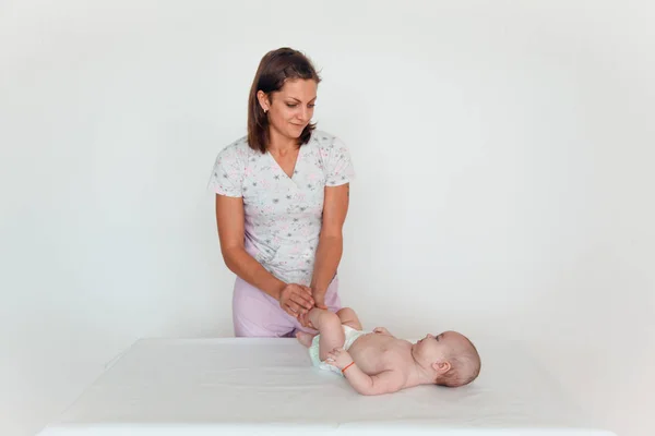 Doktor bir çocuğun beyaz bir arka plan üzerinde bacak masajlar. Bebek Masaj — Stok fotoğraf