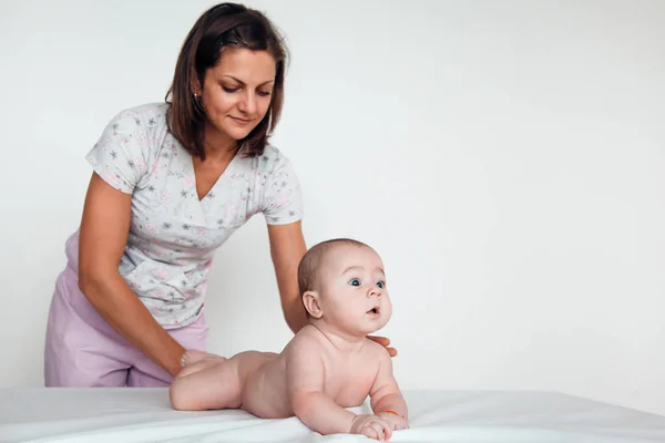 Жінка-лікар робить дитячий масаж на білому тлі — стокове фото