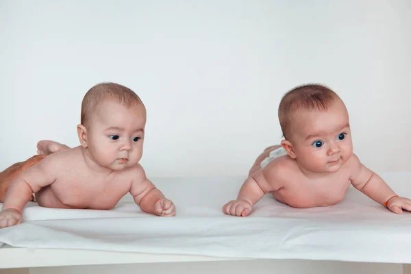 Dos bebés gemelos graciosos yacen boca abajo. Niño y niña . —  Fotos de Stock