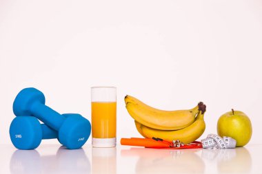 Sağlıklı bir diyet kavramı. Fintes yemek. Spor yaşam tarzı. Halter. Yeşil elma. Muz. Atlama ipi. Ölçme bant bel. Beyaz bir arka plan üzerinde
