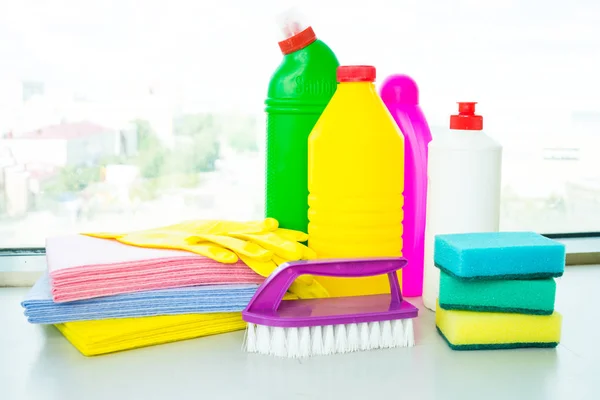 Range of cleaning products for the home. Detergents, chemical bottles, cleaning sponges and gloves. On the background of the window.