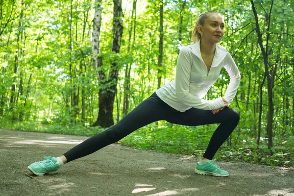 Giovane donna che fa stretching ed esercizio prima di fare jogging in un bellissimo parco — Foto Stock