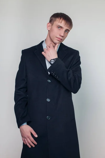 Ernstige jonge kerel in zwarte jas poseren in de studio. Mode. Schoonheid. Seizoen. — Stockfoto