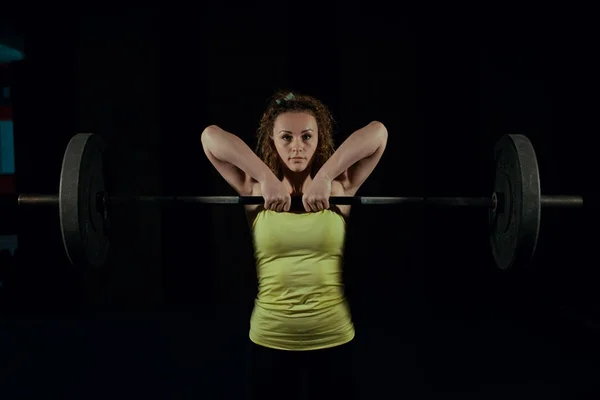 Una joven está levantando una barra en el gimnasio. Deporte — Foto de Stock